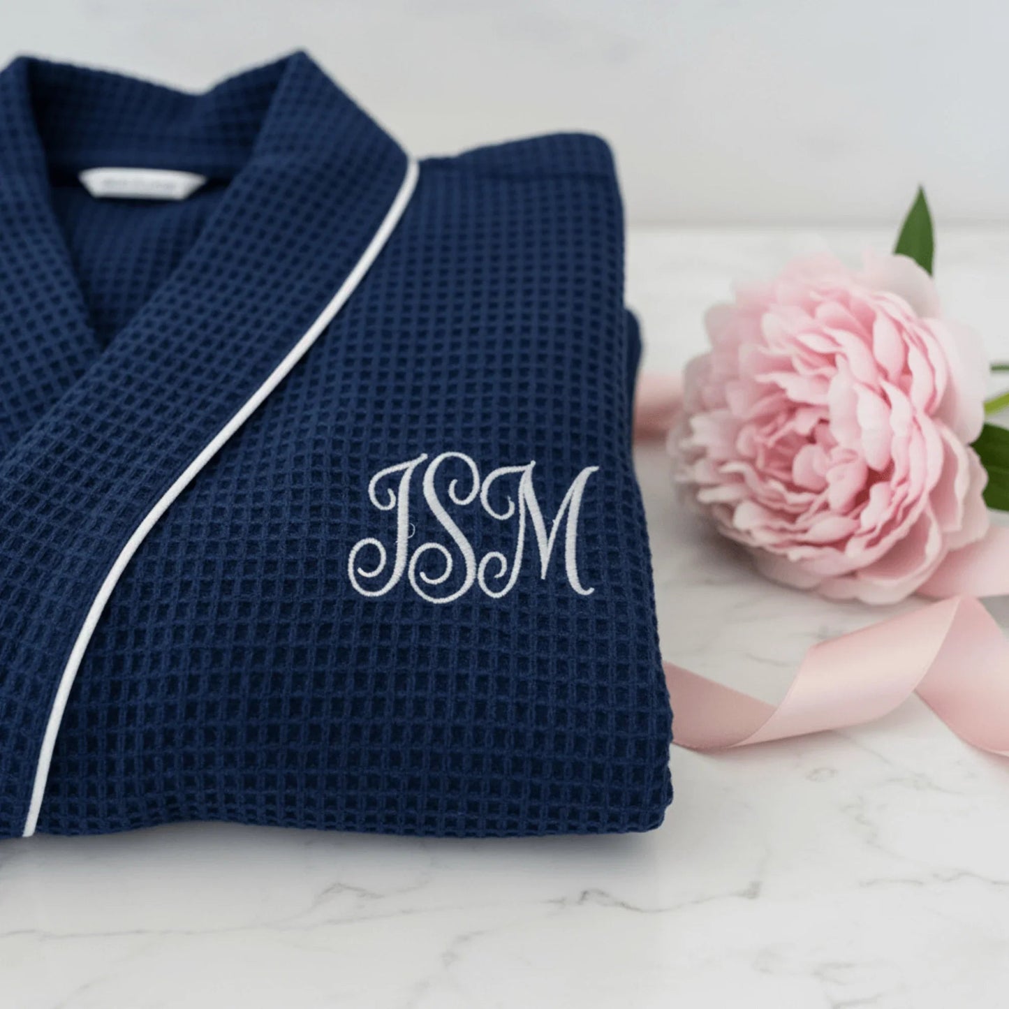Navy waffle robe close-up with white piping and 'JSM' monogram