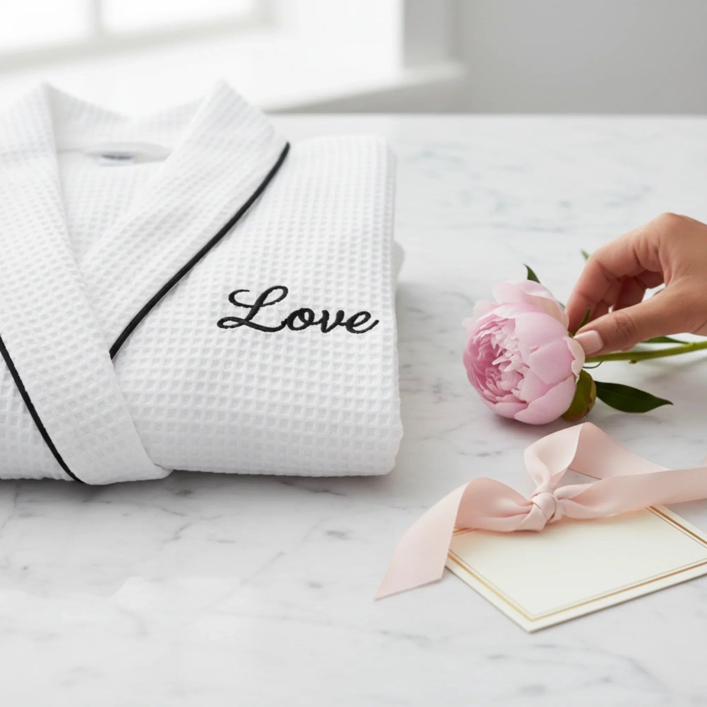 White waffle bathrobe with black piping and “Love” logo on front pocket