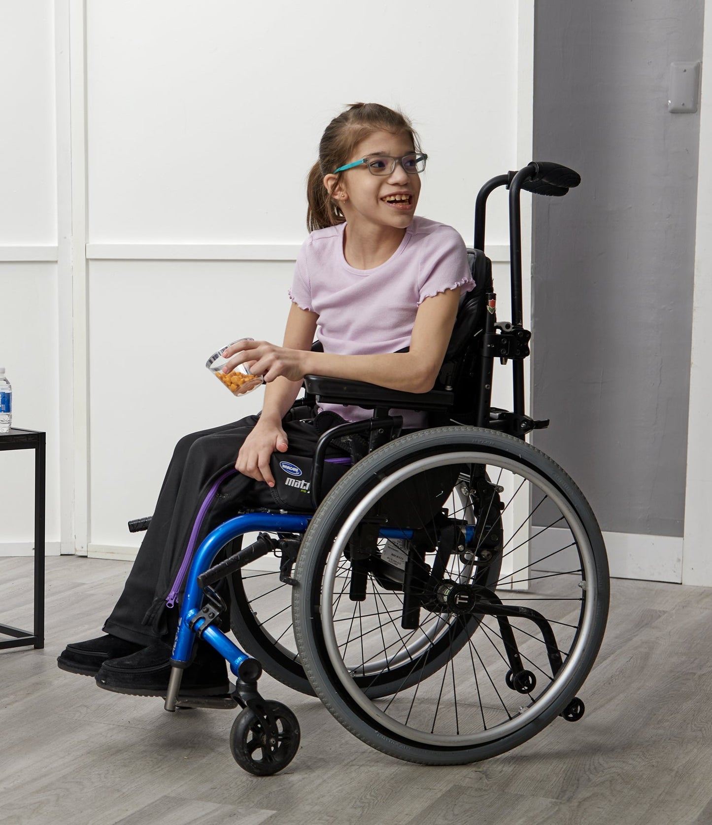 Young girl in a wheelchair smiling indoors